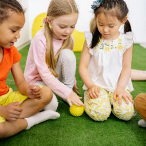 Young children of diverse backgrounds playing indoors with a ball.
