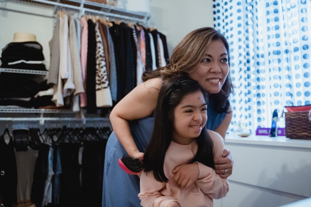 Mother and daughter enjoying a bonding moment in a cozy indoor setting, smiling warmly.